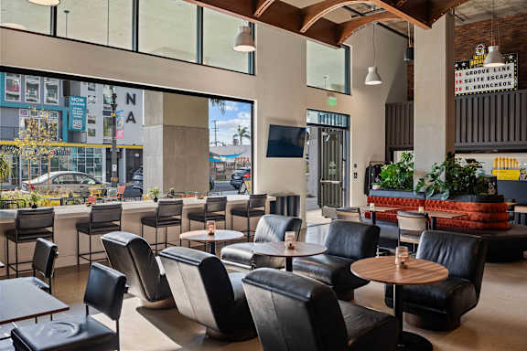 Lounge area with leather chairs and wood tables at AMP 30 Apartments, San Diego, 92116