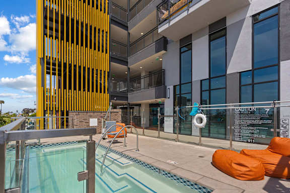 Pool deck with spa and orange seating at AMP 30 Apartments, California