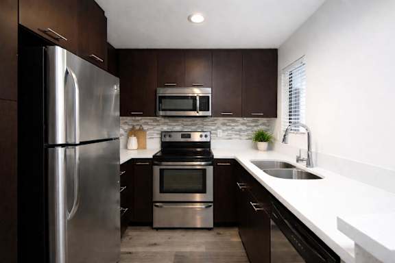A modern kitchen with dark wood cabinets and stainless steel appliances.