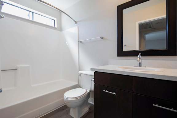 A white toilet sits in a bathroom with a sink and mirror.