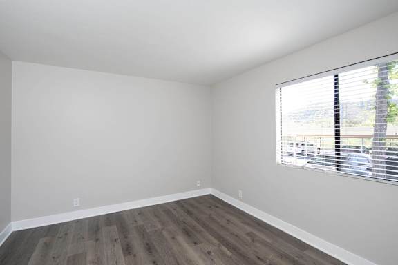 A room with a window and wooden flooring.