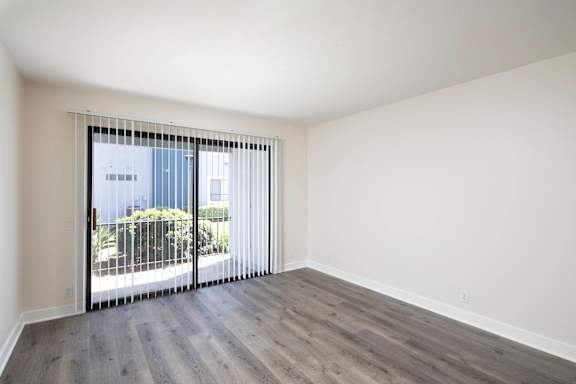 A room with a sliding glass door leading to a balcony.
