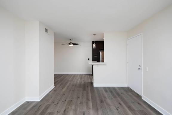A room with a ceiling fan and a wooden floor.