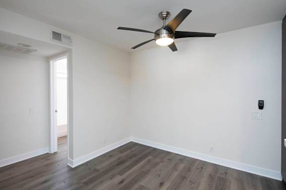 A room with a ceiling fan and wooden flooring.
