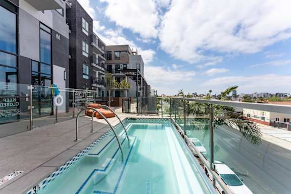 Rooftop pool with glass railings and city views at AMP 30 Apartments, San Diego, CA 92116