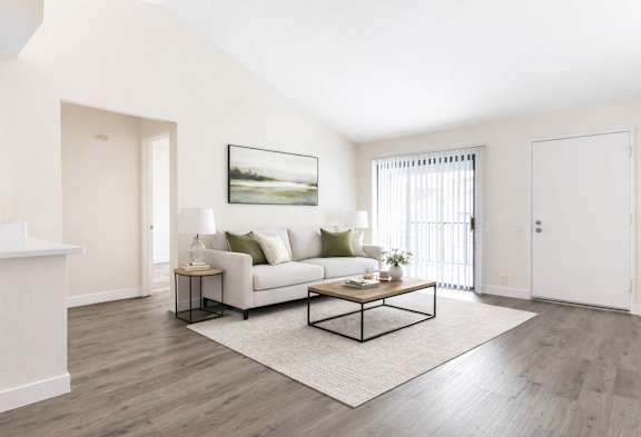 A living room with a white couch and a painting on the wall.