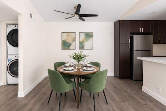 A dining room with a table set for two and a ceiling fan.