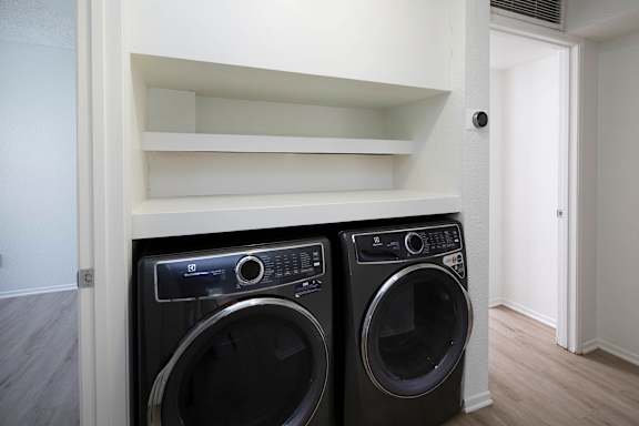Two black front load washing machines in a laundry room.