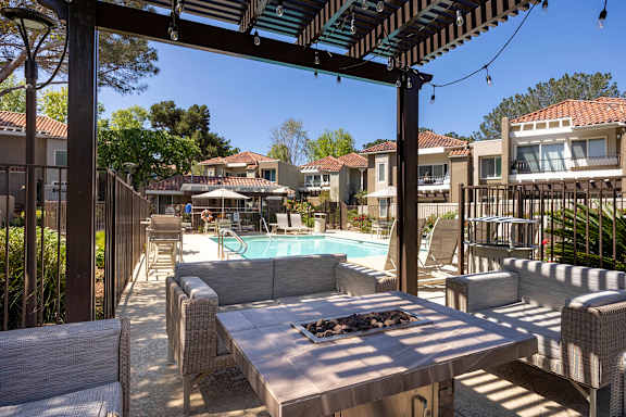 Poolside pergola with wicker seating and firepit at Bella Del Mar Apartments, California