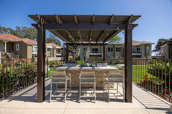 Outdoor barbecue station with bar stools under pergola at Bella Del Mar Apartments, Del Mar, CA 92014