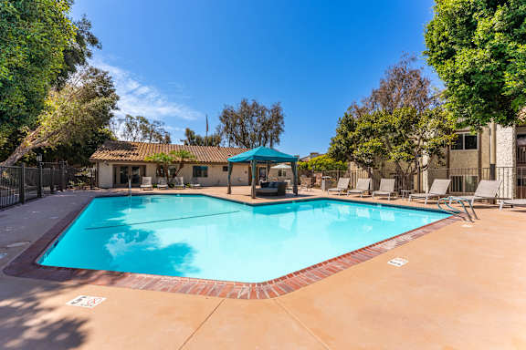 A swimming pool surrounded by trees and chairs.