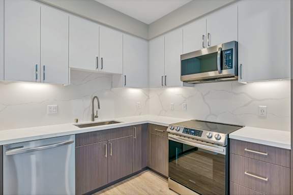 A modern kitchen with a stainless steel oven and white cabinets.