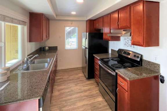 A kitchen with brown cabinets and black appliances.