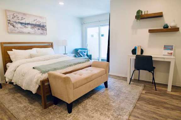 A bedroom with a bed, chair, and desk.