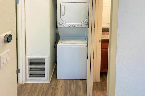 A white dishwasher is in a narrow space between a wall and a cabinet.