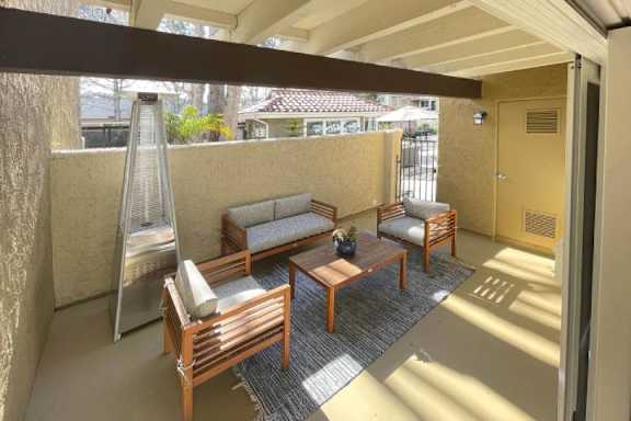 A patio with a sofa, chairs, and a table.