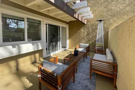 A sunny patio with wooden furniture and a hanging light fixture.