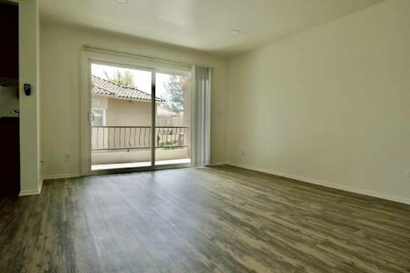 A room with a sliding glass door leading to a balcony.