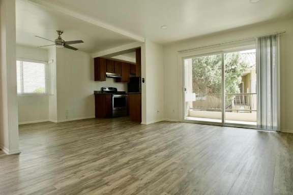 A spacious living room with a kitchen area in the background.