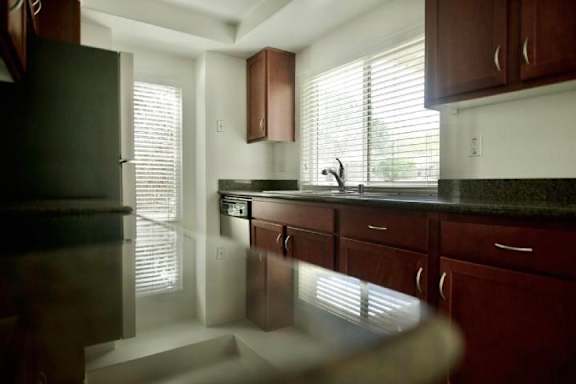 A kitchen with dark wood cabinets and a black refrigerator.
