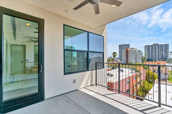 A balcony with a black railing and a ceiling fan.