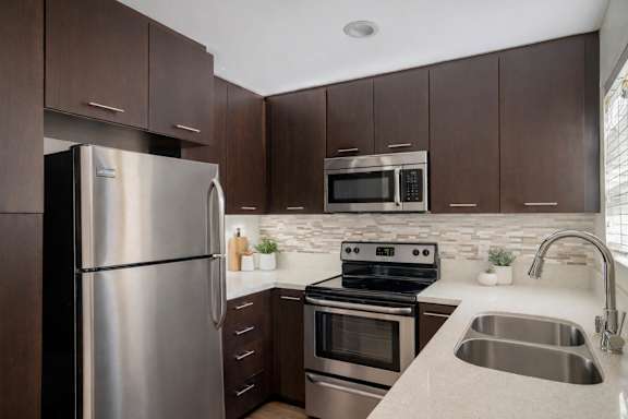 A modern kitchen with a stainless steel refrigerator, microwave, oven, and sink.