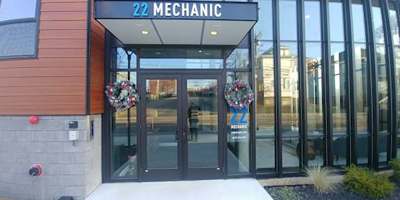 The front of a building with a glass door and a sign that says "22 Mechanic" above it.