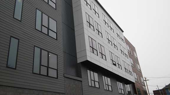 A building with a grey facade and a white building attached to it.