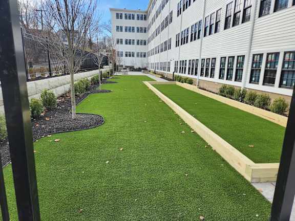 A long, narrow grassy area in front of a building.