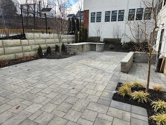 A patio with a black fence and a white house in the background.