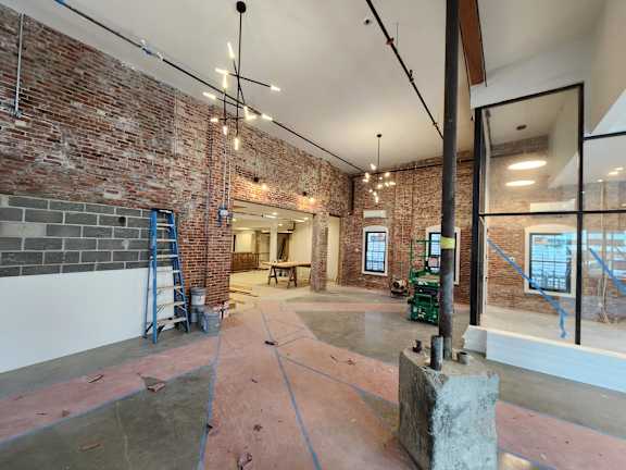 A room under construction with exposed brick walls and unfinished floors.