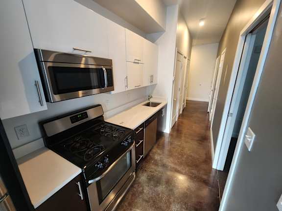 Narrow galley kitchen with stainless steel range and microwave at 68 Beale Apartments, Quincy, MA