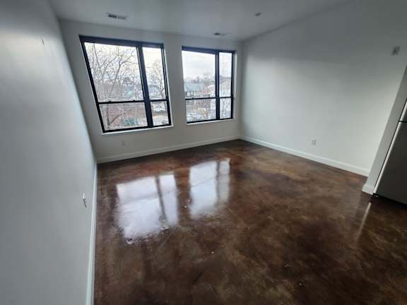 Empty room with dark polished floors and black framed windows at 68 Beale Apartments, Quincy, Massachusetts