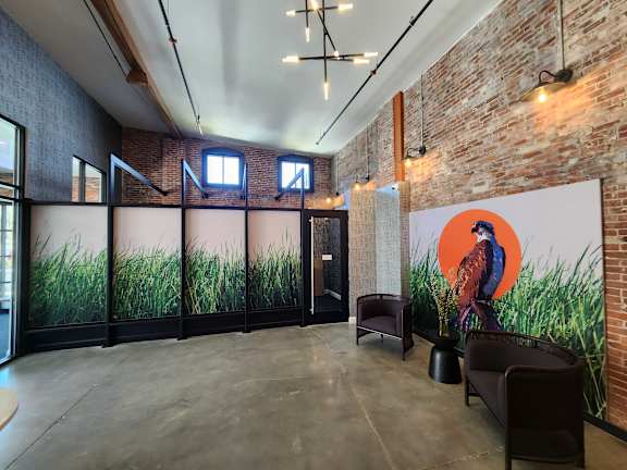 A room with a large mural of a bird on the wall and a glass partition with a view of greenery.