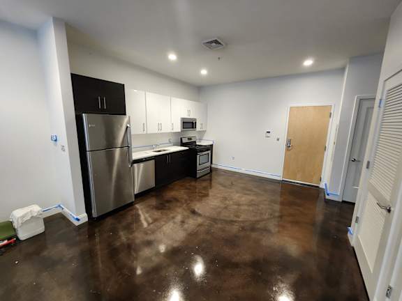 A kitchen with brown floors and white walls.