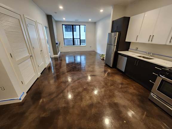 A kitchen with a brown floor and white cabinets.