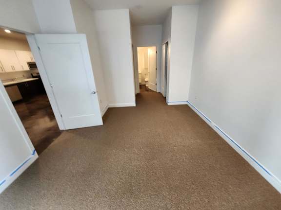 A long, narrow hallway with a carpeted floor and white walls.