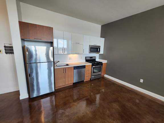 A kitchen with a refrigerator, microwave, oven, and cabinets.
