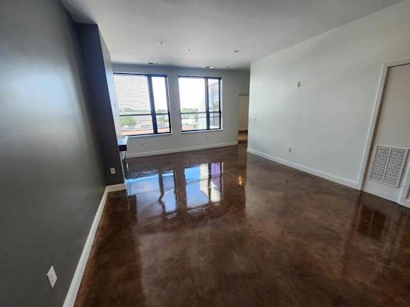 A room with brown flooring and a large window.
