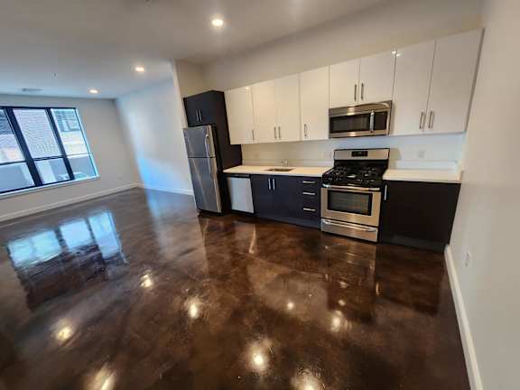 A kitchen with dark wood floors and white cabinets.