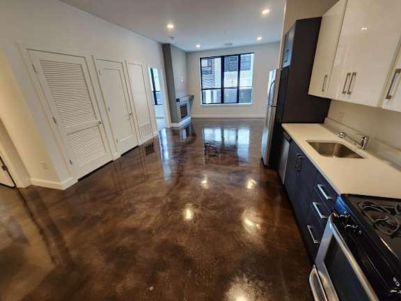 A kitchen with dark brown flooring and white cabinets.