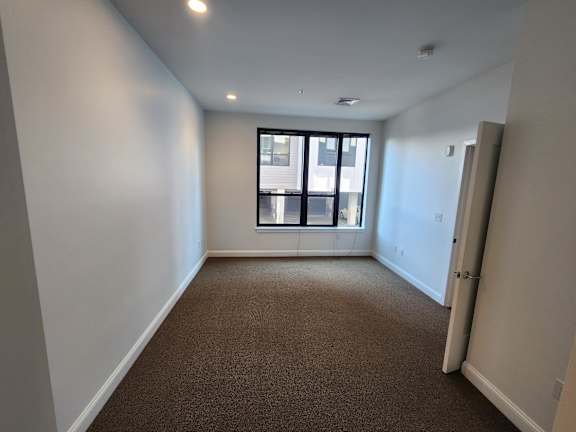 A room with a carpeted floor and a window.