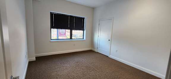 A room with a window and carpeted floor.