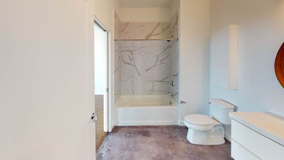A bathroom with a marble tub surround and a toilet.
