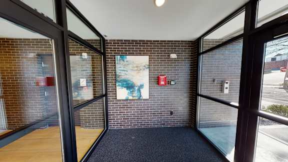 A hallway with a brick wall and a painting on it.