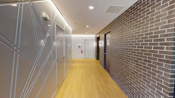 A long hallway with a brick wall on the side and a wooden floor.