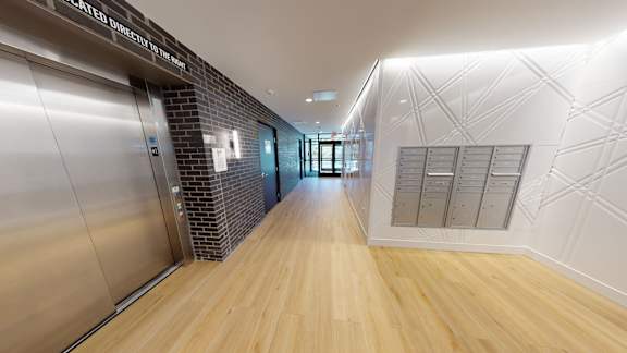 A long hallway with a brick wall and wood floors.