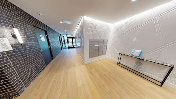 A hallway with a brick wall on the left and a glass display case on the right.
