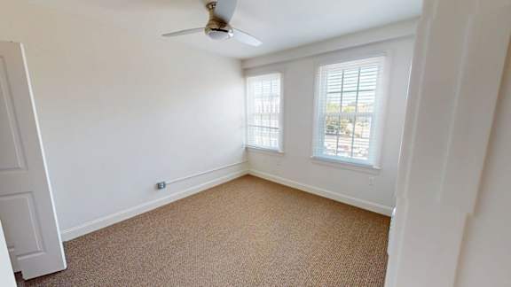 Empty bedroom with carpet and two windows at Bostonian Shoe Lofts Apartments, Whitman, MA 02382