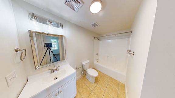 Bathroom with white tub surround and yellow tile flooring at Bostonian Shoe Lofts Apartments, Whitman, MA